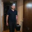 Klempner vom Notdienst betritt nachts mit Stirnlampe und Werkzeugkoffer eine Wohnung